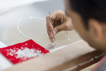 Closeup of handicraft man embroidering crystal beads onto tulle.
