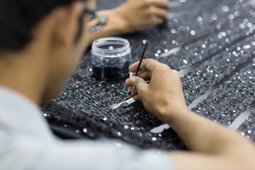 Handicraft tailor embroidering black sequins beads onto tulle. Making a dress. - obrazy, fototapety, plakaty