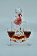 Fluffy pink flamingo in retro setting with crystal decanter and port or sherry wine glasses