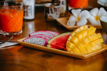 The fruit in the tray has dragon fruit, mango, watermelon and fruit juices set in the background.