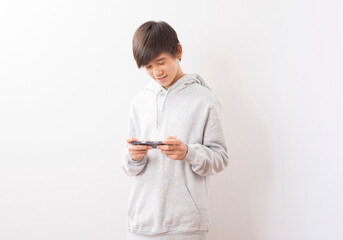 Asian teen boy schooler texting or playing game online on smartphone isolate on white background.