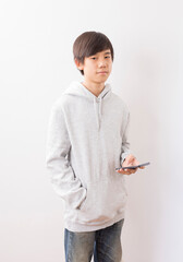 Fototapeta premium Asian teen boy schooler texting or playing game online on smartphone isolate on white background.