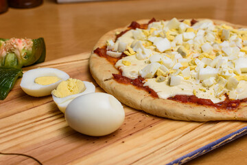 Pizza con huevos duros sobre tabla de madera