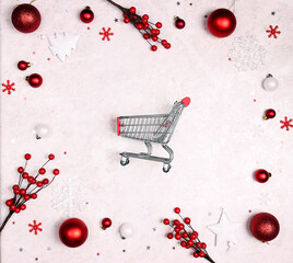 Shopping trolley cart surrounded by white and red decorations on a light marble background.