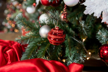 Closeup of red and white bauble hanging from a decorated Christmas branch. abstract background with defocused lights.Room decorated for the new year and Christmas.