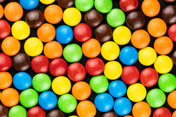 Top view of multicolored chocolate candy bean on black background.