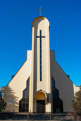 Catholic white tower church with big cross on a deep blue sky