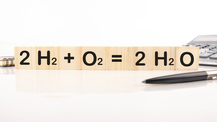 Reaction of Hydrogen and Oxygen to water inscription on wooden cubes on a white background 2H2 plus O2 equals 2H2O