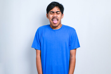 Boy wearing casual shirt sticking tongue out happy with funny expression. Emotion concept. © Reza