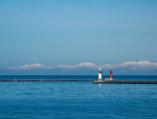 雪山と防波堤の赤白灯台