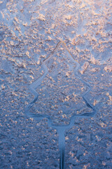 drawing of a fir on an icy winter window. christmas theme. cold winter 2022 patterns on the winter window the glass outside the window is frosty. Cold weather