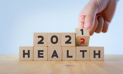 Health management and trend concept in 2022. Medical healthcare business and personal healthcare. Hand flips wooden cubes 2021 to 2022 with text "HEALTH" on beautiful white background and copy space.
