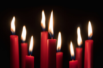 Many red candles burning in front of black studio background
