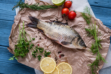 Fresh raw whole fish of mirror carp with spices, lemon and herbs on a background of craft paper