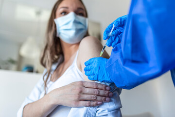 Female doctor giving the coronavirus vaccine to a young pregnant woman. Antibodies, immunize population. side effects, risk people, antibodies, new normal, covid-19. Vertical photo - obrazy, fototapety, plakaty