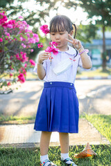 PHRAE, THAILAND – NOVEMBER 20: Asian girl in kindergarten uniforms is happy outside the building on the December 20,2021 in PHRAE,TH.