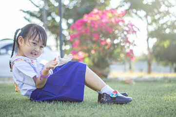 PHRAE, THAILAND – NOVEMBER 20: Asian girl in kindergarten uniforms relaxes outside the building on the December 20,2021 in PHRAE,TH.