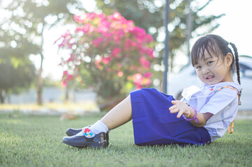PHRAE, THAILAND – NOVEMBER 20: Asian girl in kindergarten uniforms relaxes outside the building on the December 20,2021 in PHRAE,TH.