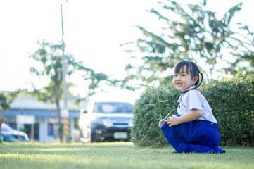 PHRAE, THAILAND – NOVEMBER 20: Asian girl in kindergarten uniforms relaxes outside the building on the December 20,2021 in PHRAE,TH.