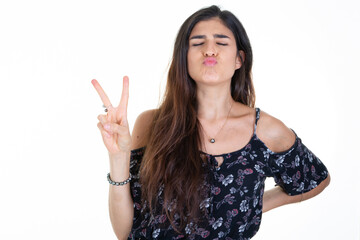 Young woman smiling happy face showing two fingers v positive and peace gesture on white background