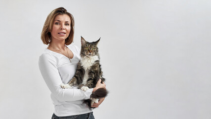 European woman hold furry Maine Coon cat in hands