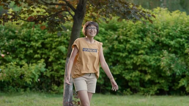 Woman plays frisbee on grass lawn. Summer vibes. Outdoor leisure activity. Family life. Sports game at backyard.