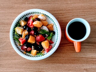 A cup of coffe and fruit salad
