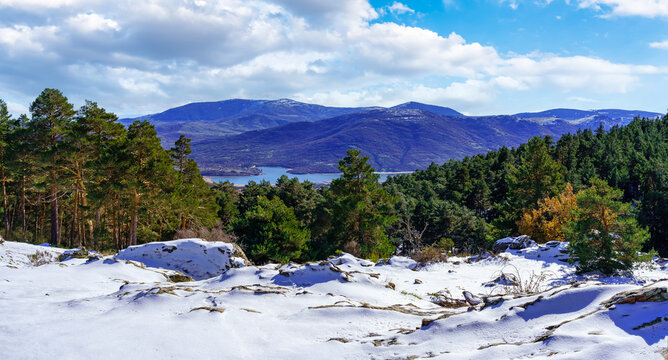 Panoramic mountain landscape with freshly fallen snow in the valley and lake in the background. Guadarrama, Madrid.