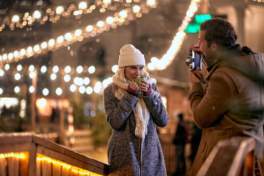 Couple enjoying at christmas festival on a snowy weather and take picture