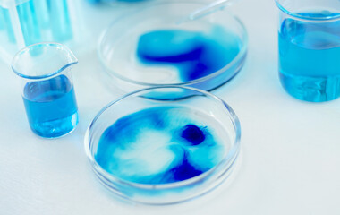 Laboratory glassware with blue and cyan liquid on a white table. Scientific laboratory research. Antiviral vaccine development.