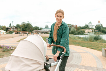 Young Mother walking with baby carriage in park