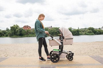 Mother with baby carriage walking near water