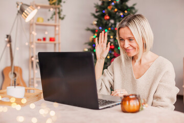 Excited adult 40s woman waving hello with hand, using laptop at home - Powered by Adobe
