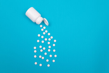 Global Pharmaceutical Industry and Medicinal Products - White Pills or Tablets Scattered from the Bottle, Lying on Blue Background, Top View, Flat Lay