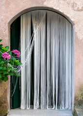 Arched entrance door with white string curtains and purple hydrangea