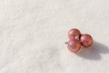 Christmas balls snow. Pink shiny Christmas decorations lie on the snow and sparkle. The concept of a holiday, gifts, congratulations. Horizontal snow banner in bright sunlight. Copy space