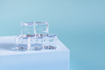 Transparent ice cubes on a blue podium and a light background of kopi space. Background of transparent ice cubes close-up and.
