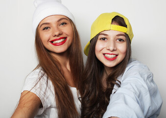 lifestyle and people concept: Two young girl friends standing together and having fun. Looking at camera.