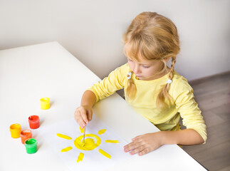 a little girl draws a yellow sun. preschool.