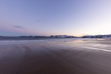A huge and wide sandy beach of the Arctic Ocean at sunset. Teriberka village, Murmansk region, Russia.