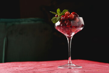 Wide champagne glass filled with fresh raw cranberries on a round marble tray, copy space