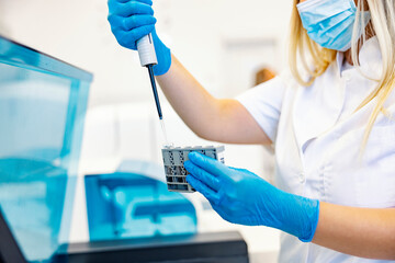 A nurse testing blood samples. A nurse is standing in the lab, holding blood samples and testing...