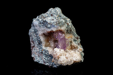 macro mineral amethyst stone in rock on a black background