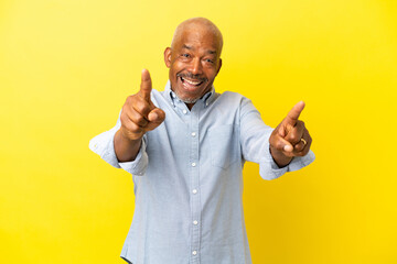 Cuban Senior isolated on yellow background surprised and pointing front