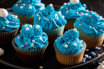 Delicious cupcakes with flower shaped blue cream.
