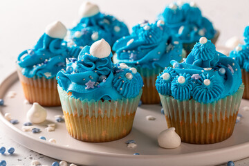 Homemade cupcakes with blue whipped cream ready to eat.