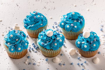 Tasty cupcakes with white sprinkles and blue cream.