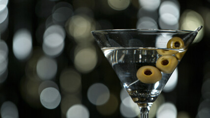 Falling olives into martini drink, freeze motion