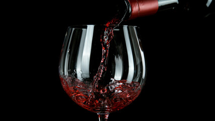 Pouring red wine, black background. Back view.