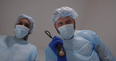 Doctor and nurse bent over the patient. He touch the pulse examines the patient, shines a flashlight in the eyes and checks reaction of pupils,  pronounced death and covered  face with a sheet.